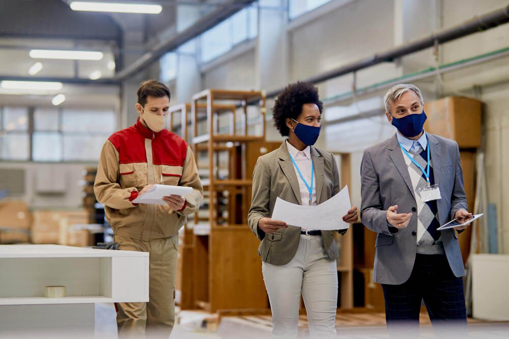 quality-control-inspectors-communicating-while-walking-through-woodworking-facility-during-coronavirus-pandemic (1)